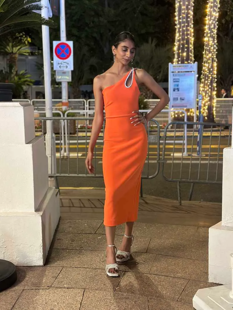 Dolly Singh makes a style statement with a pop of colour balanced with sophisticated elegance in a stunning orange dress with a beautiful strap detail at Cannes Festival 2023.